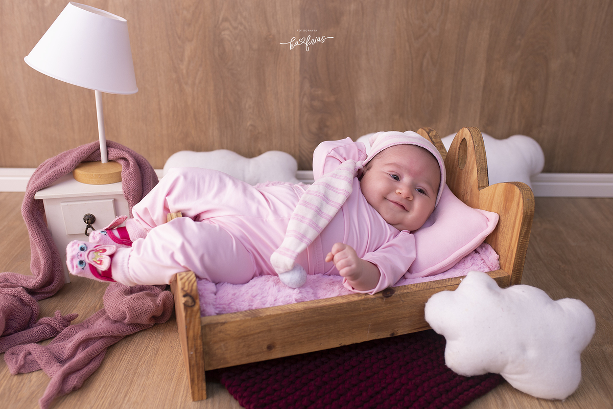 a menina esta deitada na cama para as fotos mensais