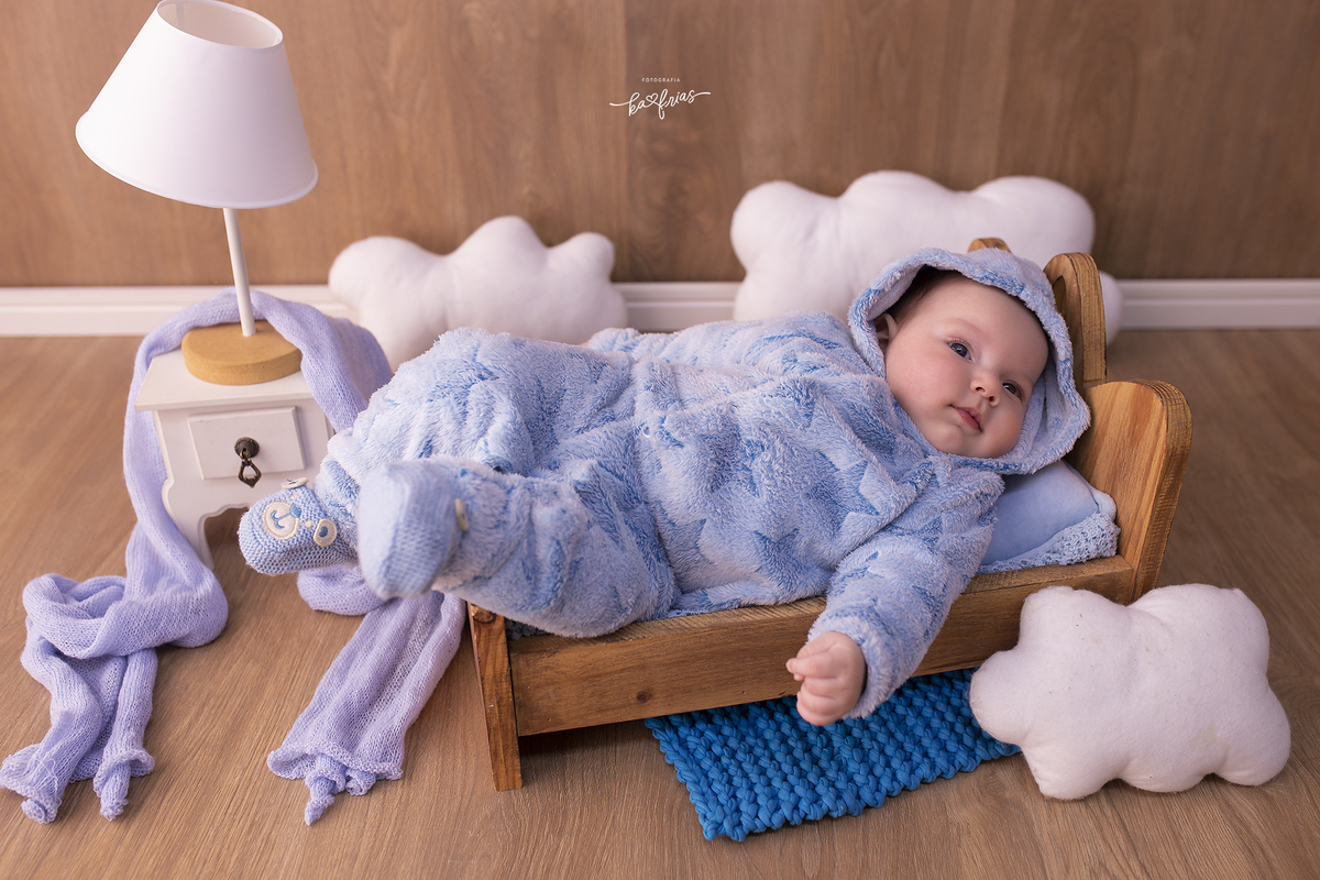 o bebe esta deitado na caminha para as fotos mensais