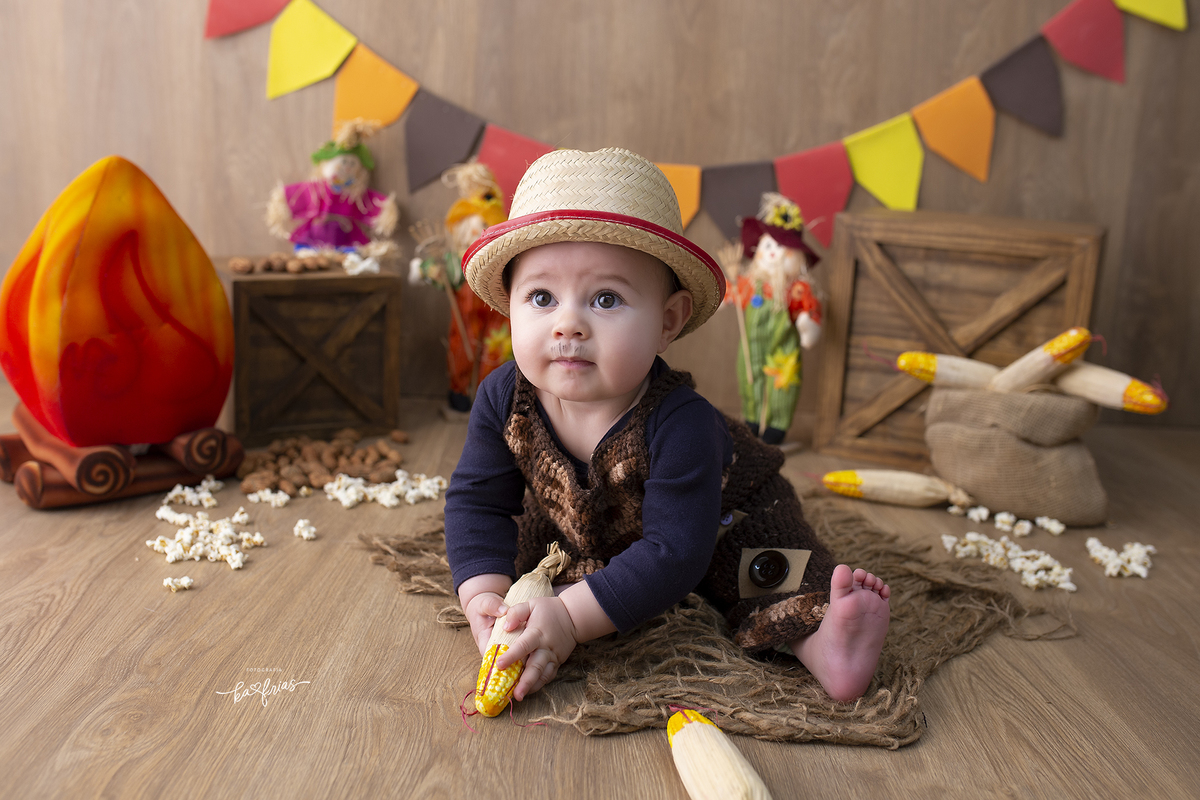 o menino brinca com o milho no cenario de festa junina