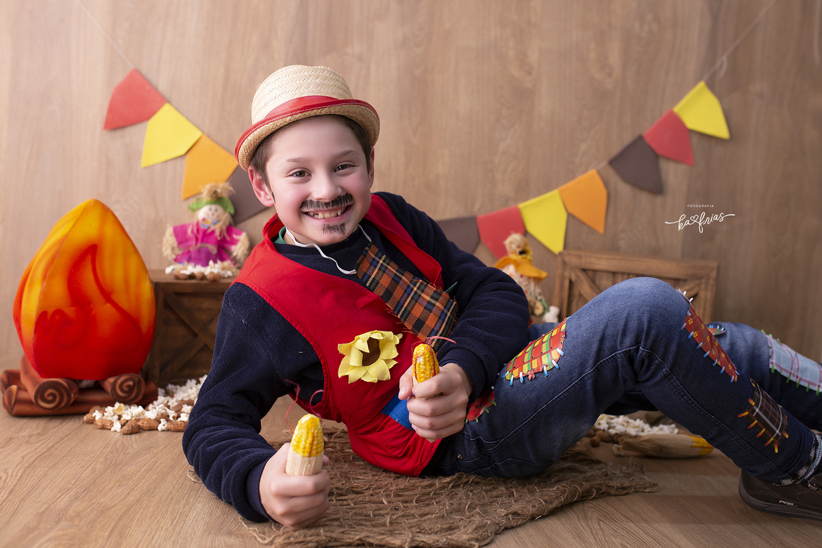 o menino mostra o milho no ensaio junino