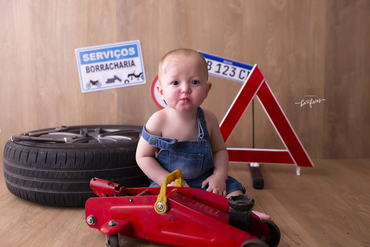o menino esta vestido de mecanico para as fotos mensais