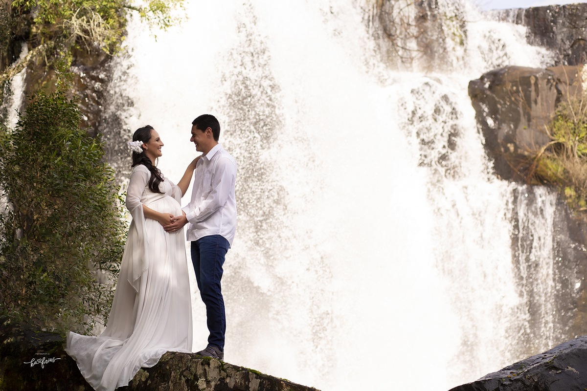 a gestante posa em frente a cachoeira para as fotos externas