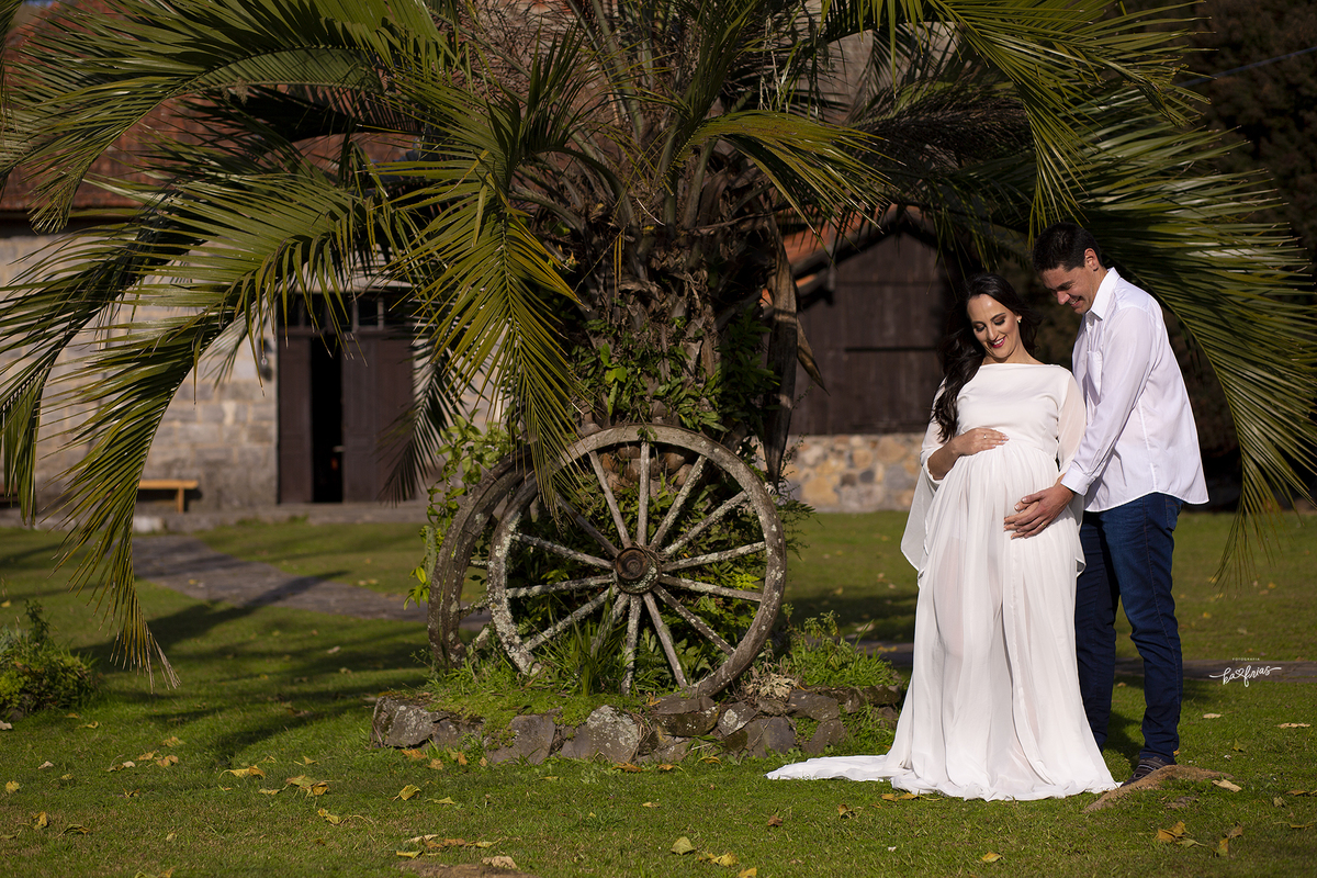 na sessão externa de gestante os pais olham para a barriga