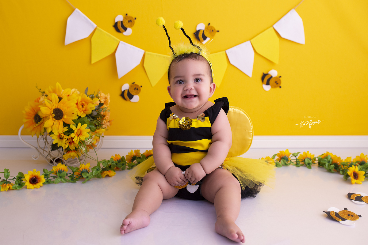 a menina esta vestida de abelha para a sessão de 9 meses