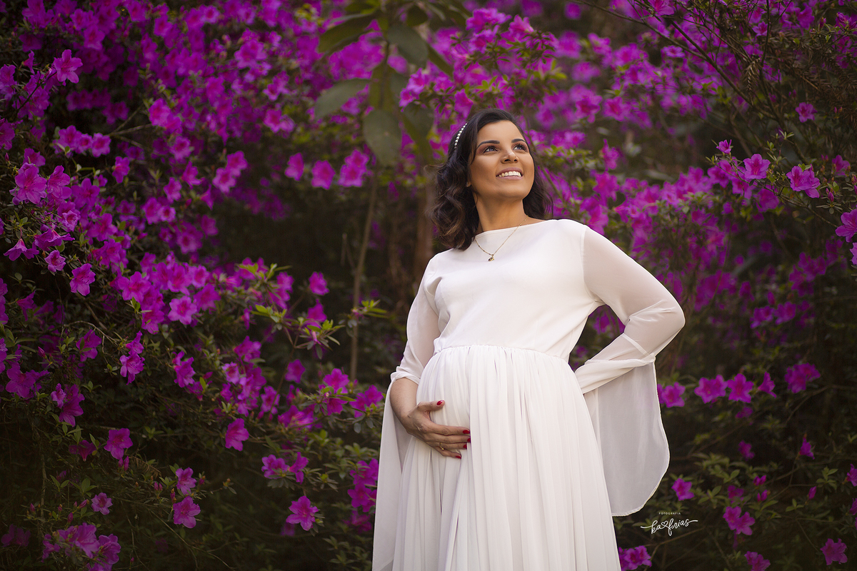 a gestante esta no meio das flores para sua sessão externa