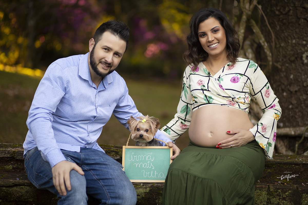 os pais posam com a cachorrinha no ensaio de gestante