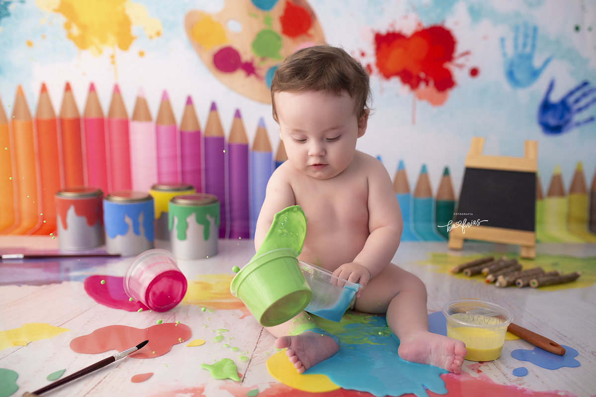 o menino brinca com as tintas na sessão de fotos