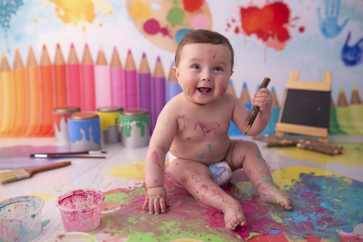 o menino brinca com as tintas na sessão de fotos