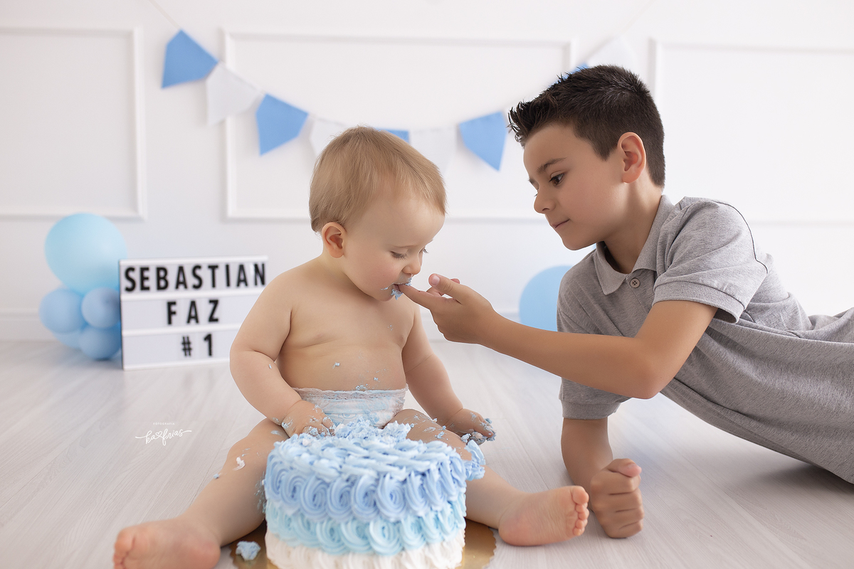 o irmao da bolo para o bebe na sessão de fotos