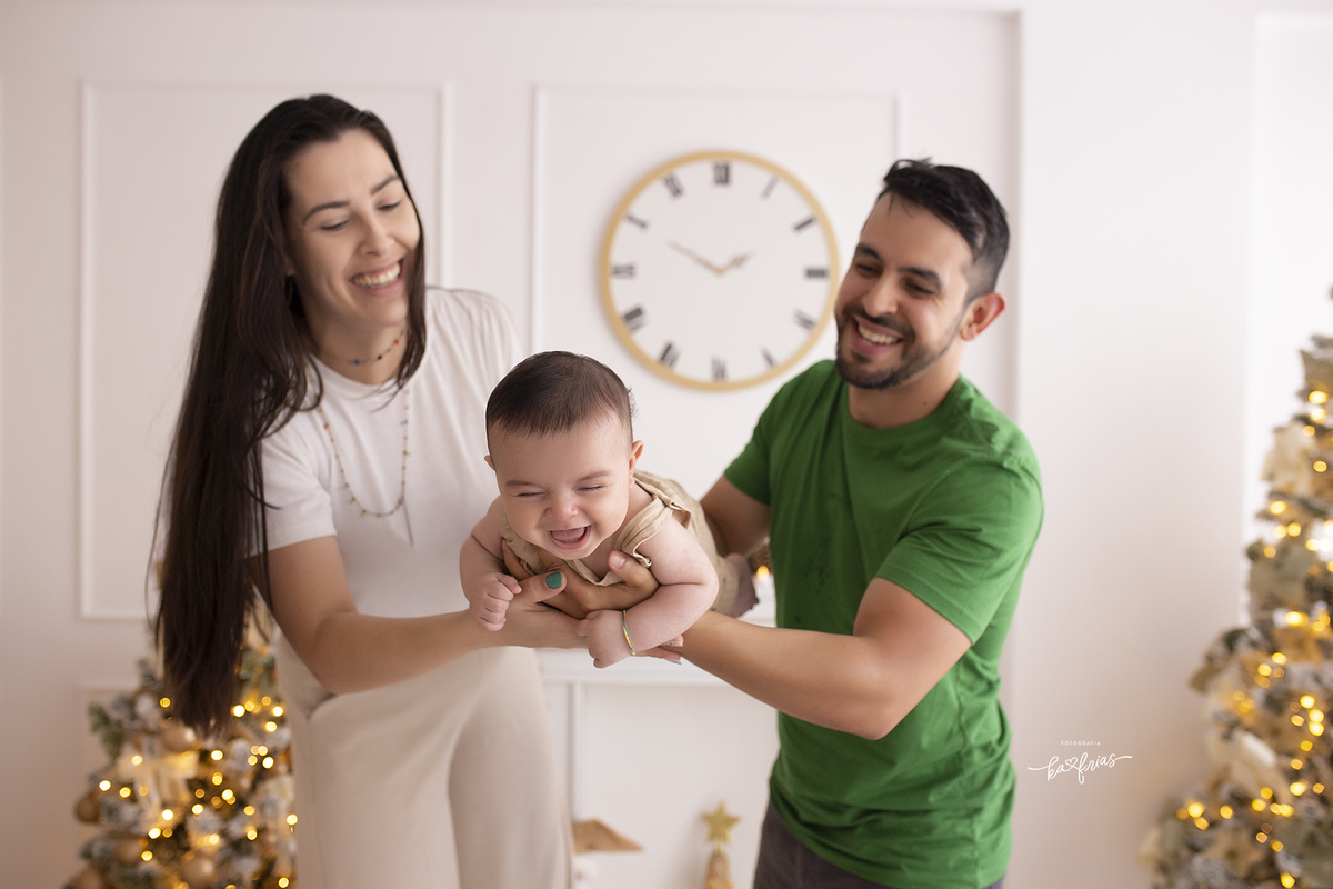 o bebe se diverte com os pais na sessão de natal