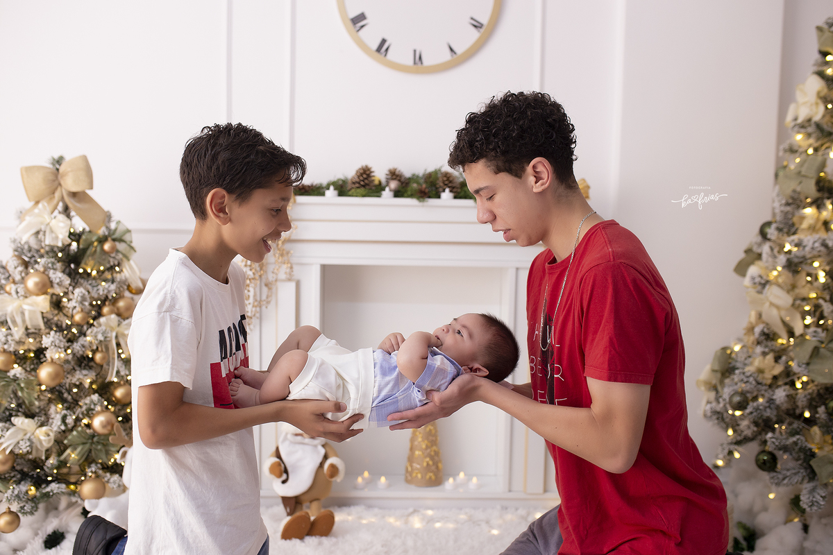 os irmaos seguram o bebe nas fotos de natal
