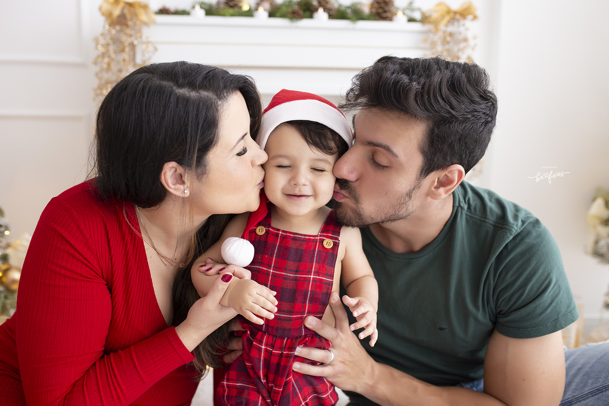 os pais beijam o bebe no ensaio de natal