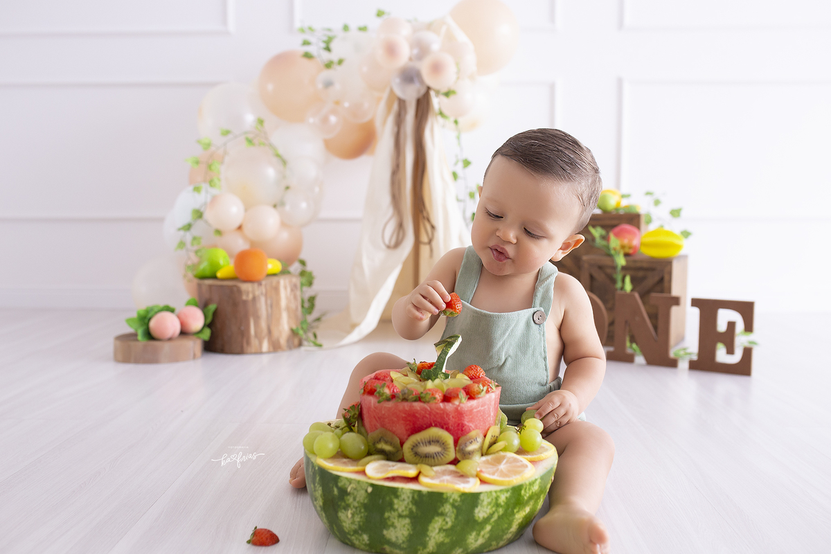 o menino come frutas no ensaio de um aninho