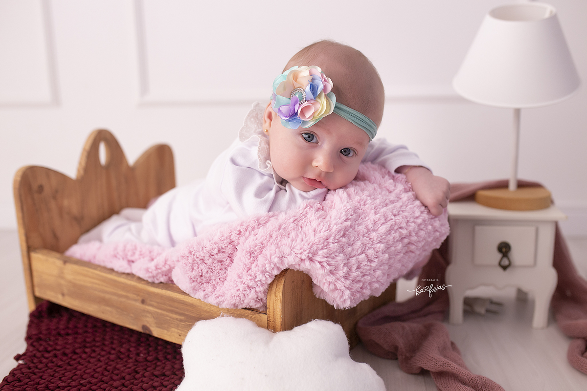 a bebe esta de bruços na cama para o ensaio infantil