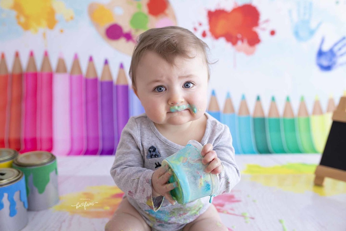 a bebe se lambuza com as tintas no ensaio infantil