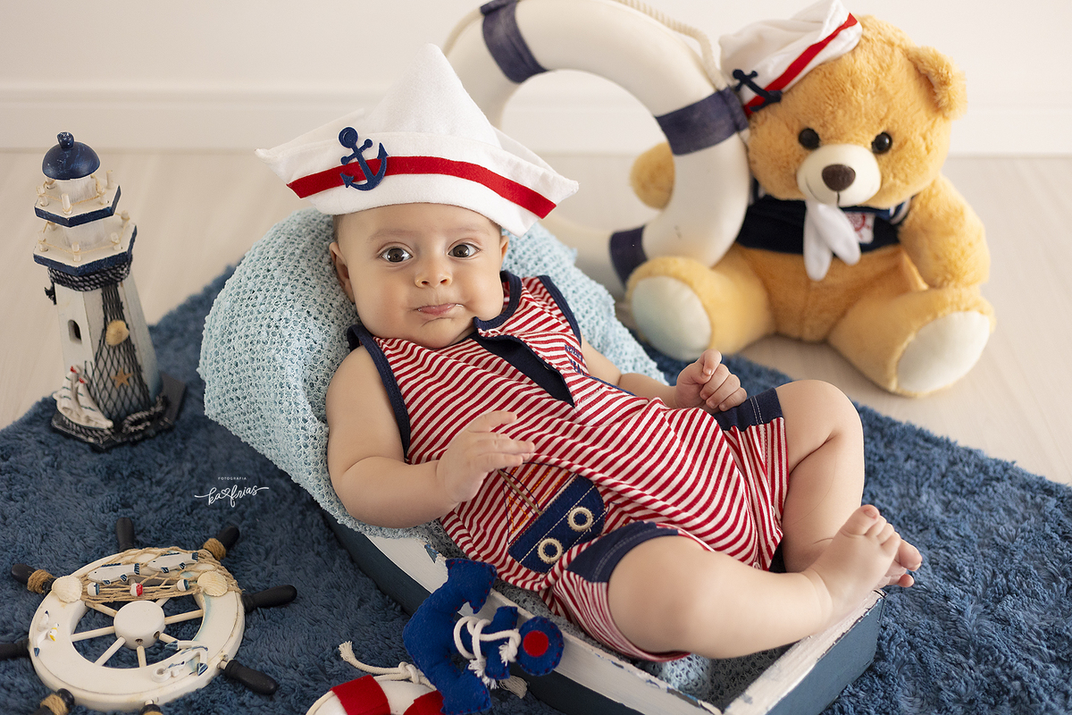o bebe esta vestido de marinheiro para as fotos mensais