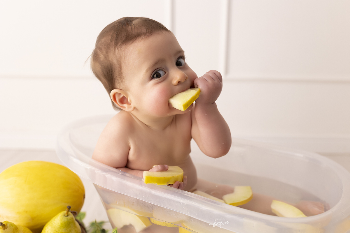 o menino brinca com as frutas na sessão de fotos