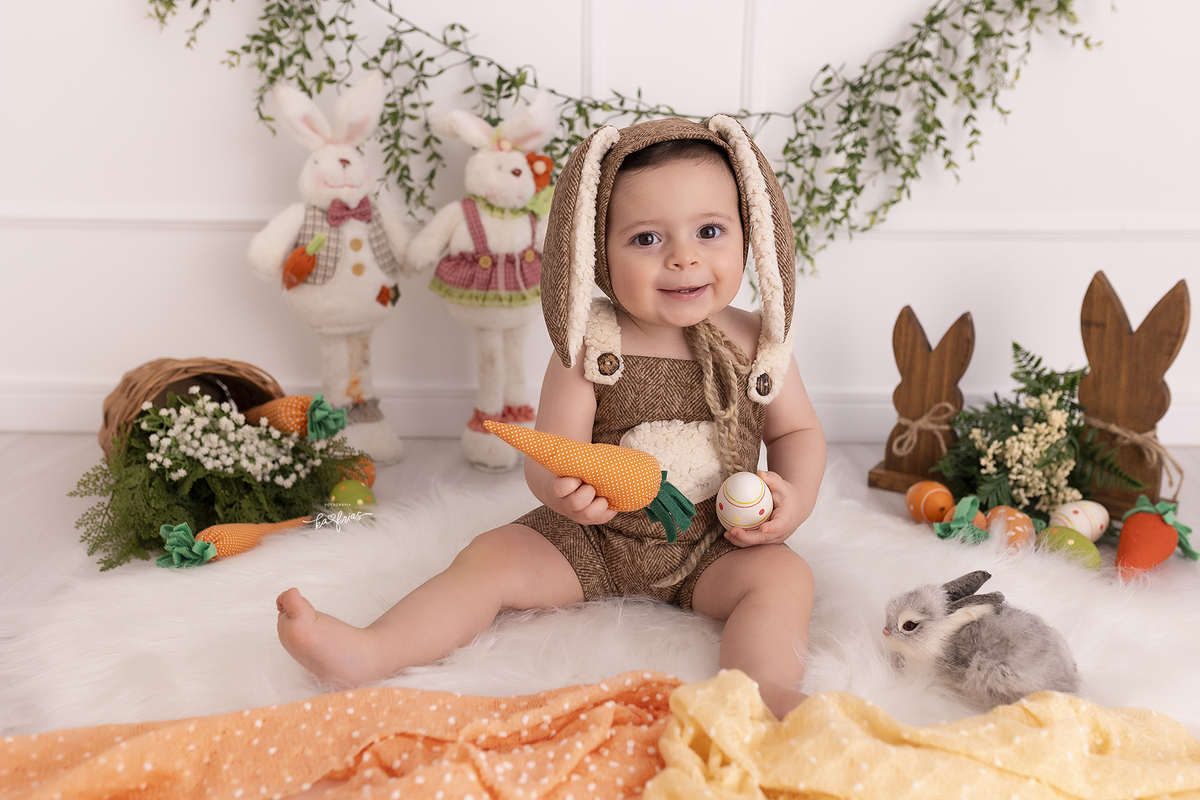 o bebe esta vestido de coelho para as fotos mensais
