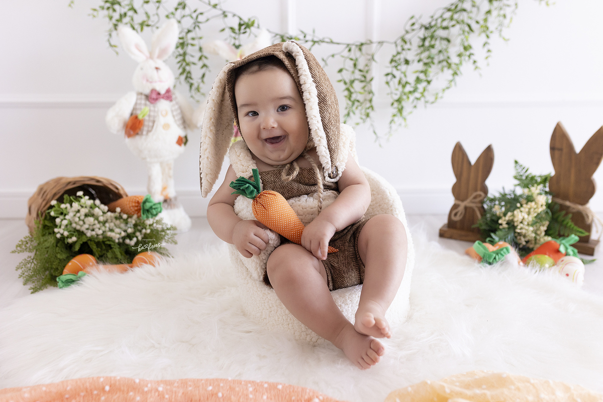 o bebe esta vestido de coelho para as fotos mensais
