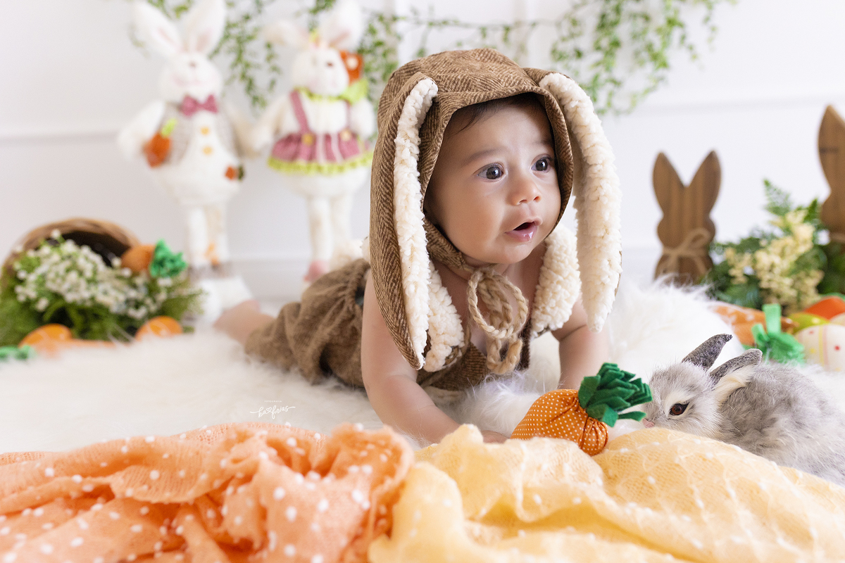 o bebe esta vestido de coelho para as fotos mensais