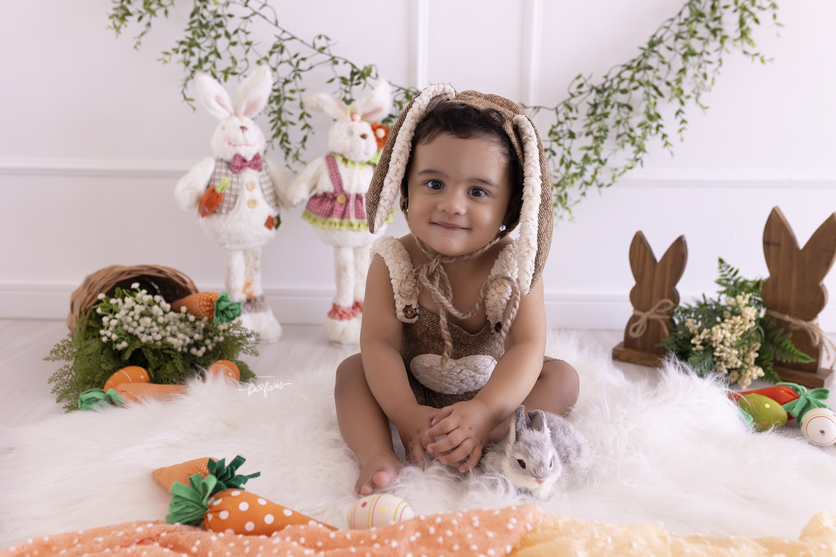 o bebe esta vestido de coelho para as fotos de acompanhamento mensal