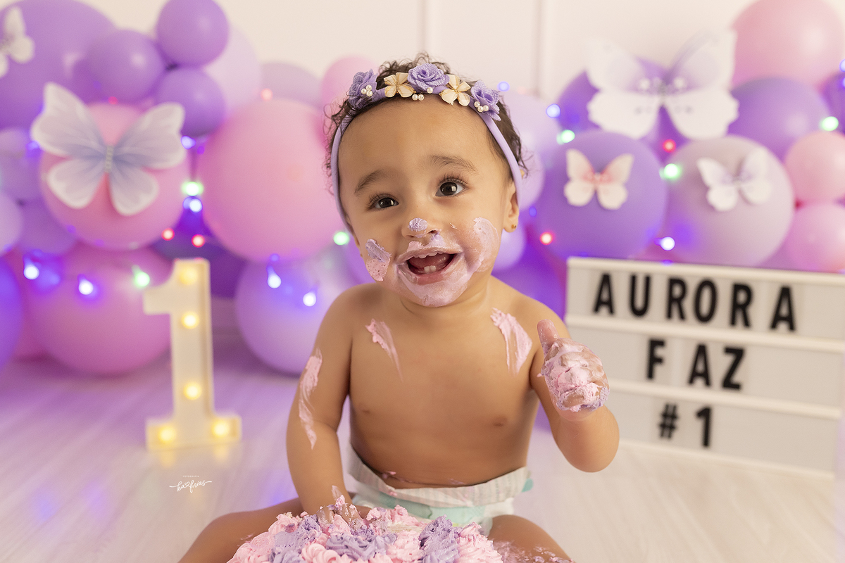 a bebe se suja com o bolo no ensaio de um ano