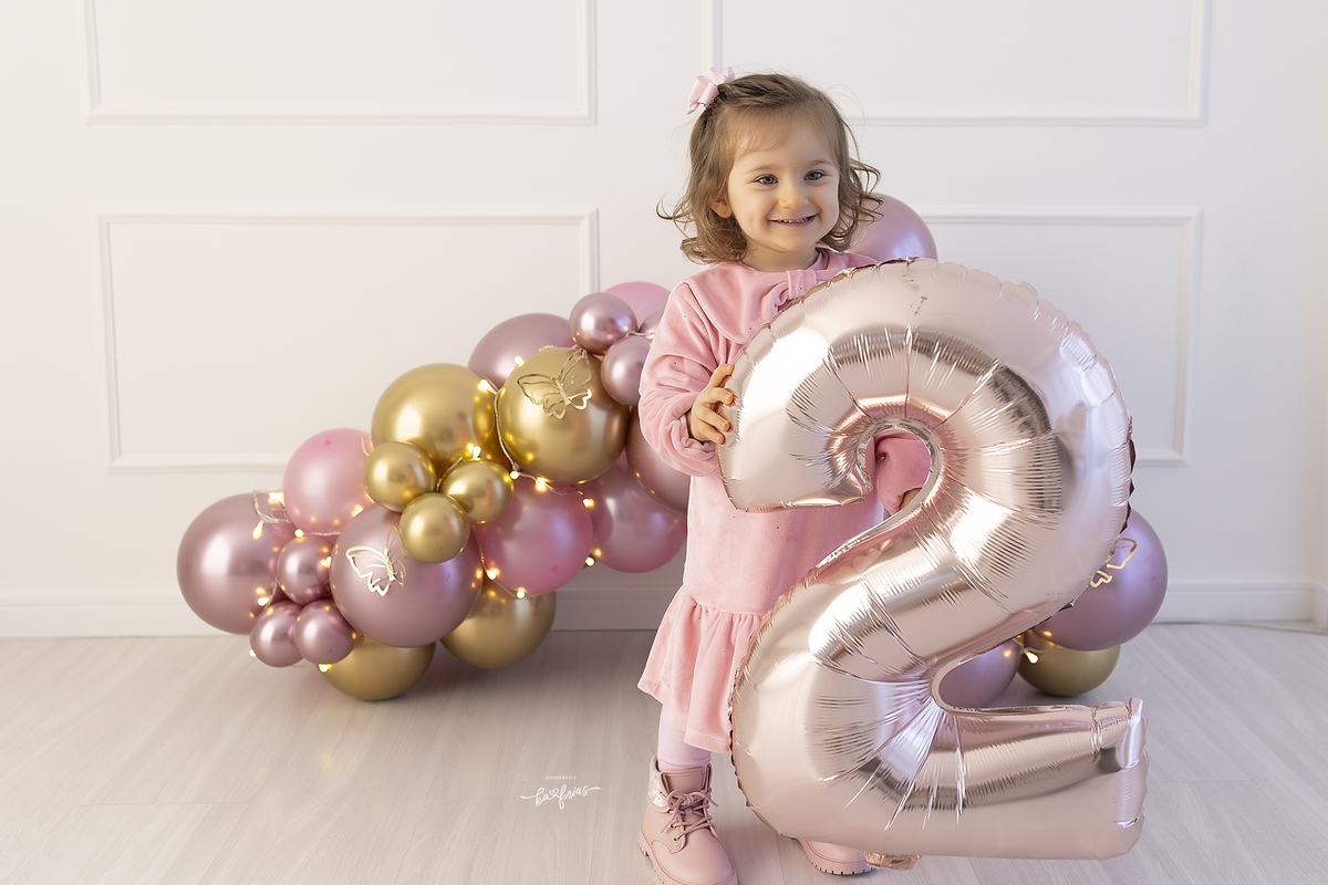 a bebe segura o balao do seu aniversario