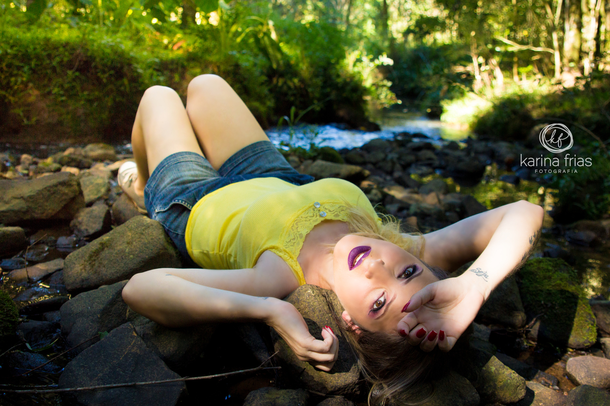 a modelo deitada nas pedras em cachoeira da própria chácara.