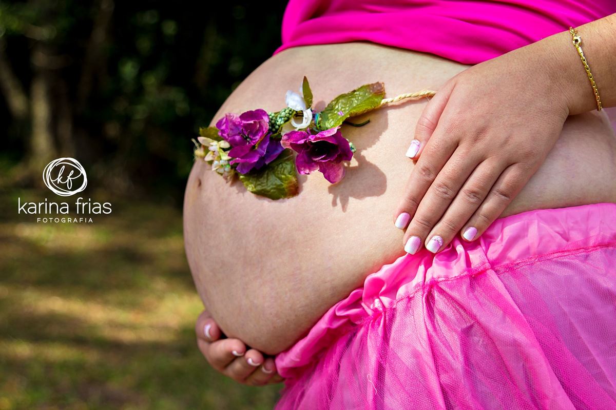 As flores contornam a barriga da gestante em seu ensaio externo
