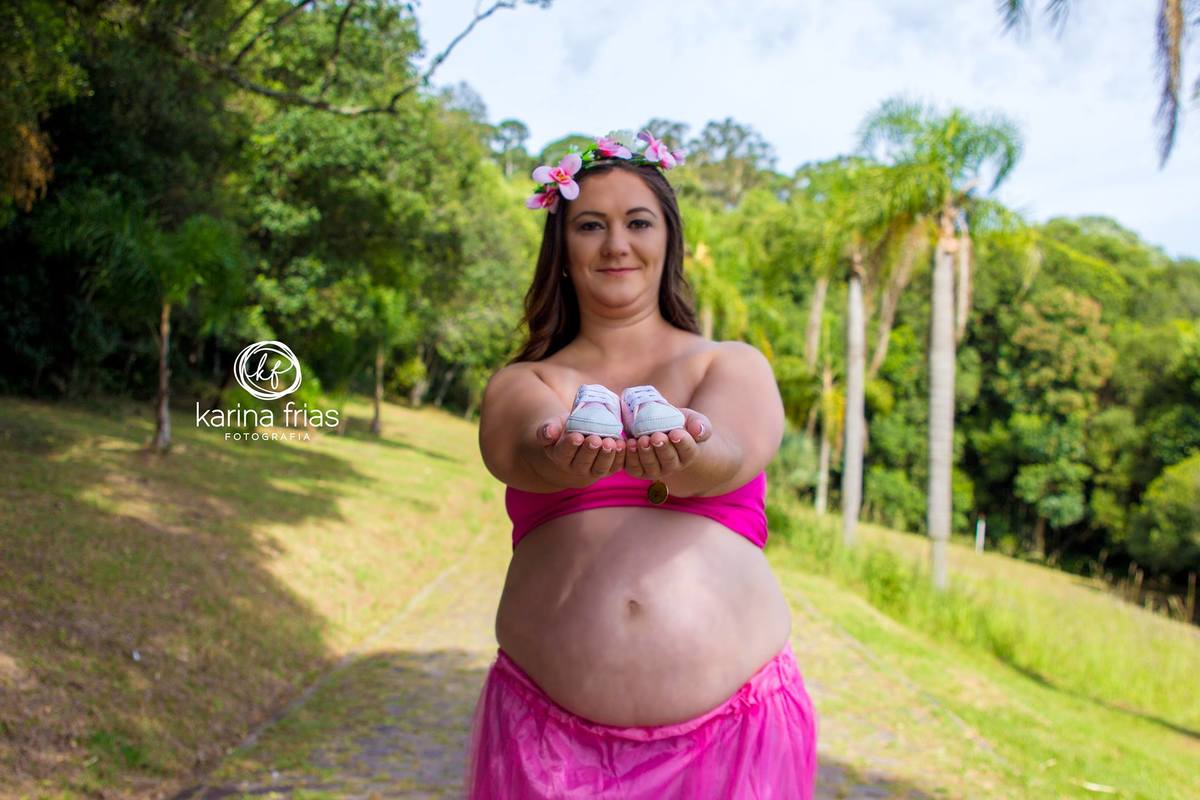 No book de gestante a modelo mostra os sapatinho do nene