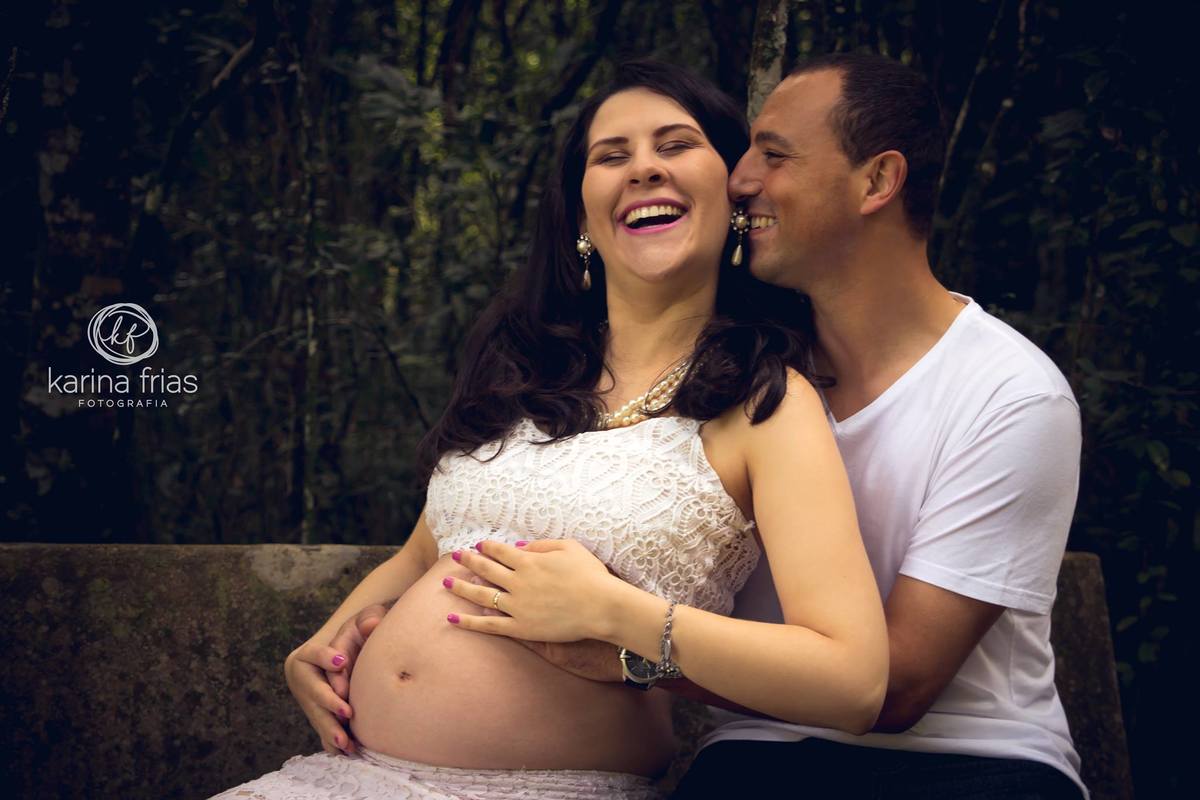 A esposa gestante sorri para o marido em sua sessão de fotos de gestante