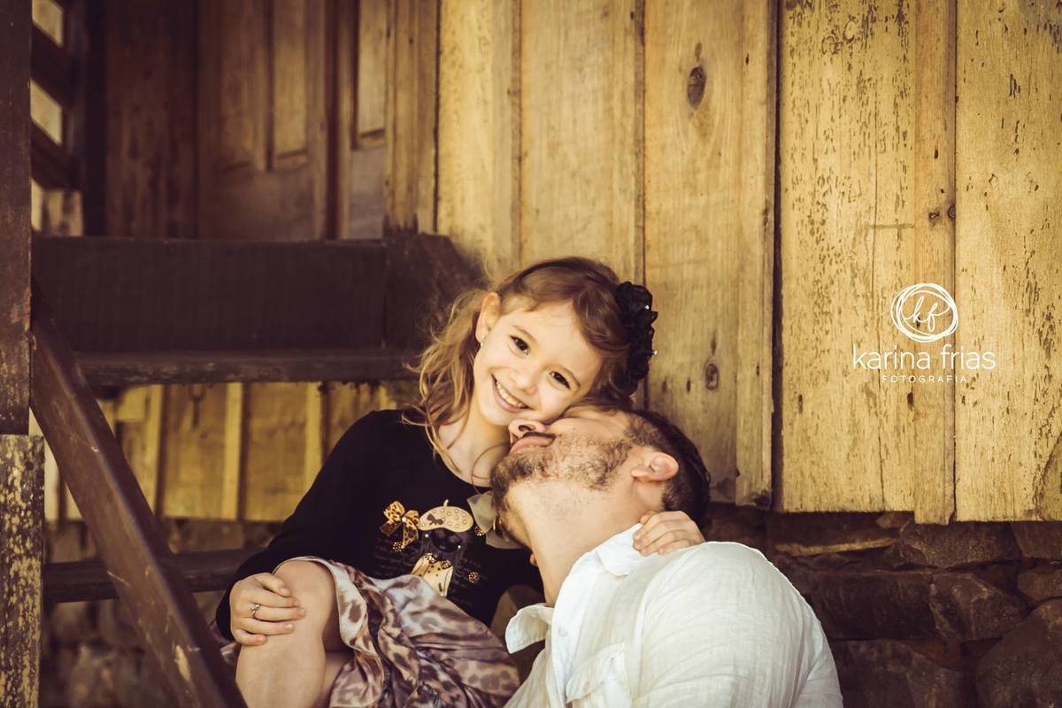 no ensaio externo infantil, o pai deita no colo da filha