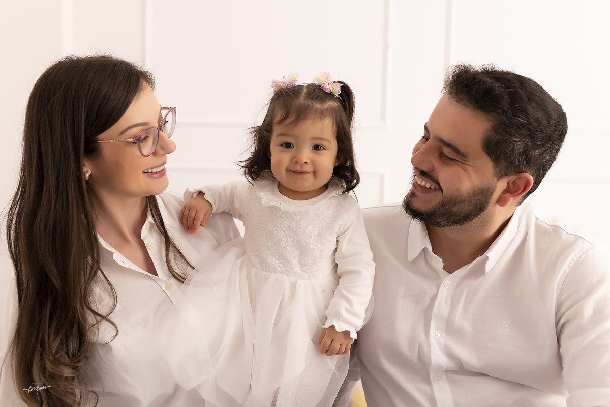 os pais sorriem para a filha no ensaio de um aninho