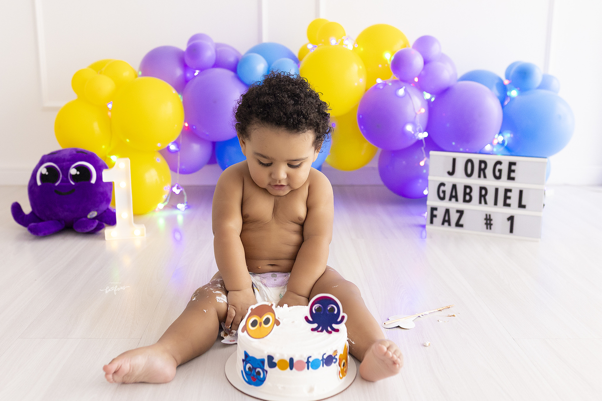 o menino se suja na sessão de fotos com bolo
