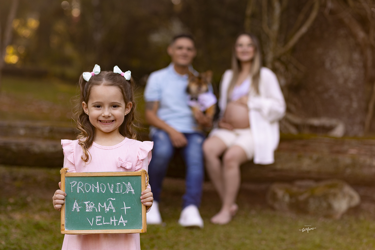 a irma segura o quadro nas fotos de gestante da mae