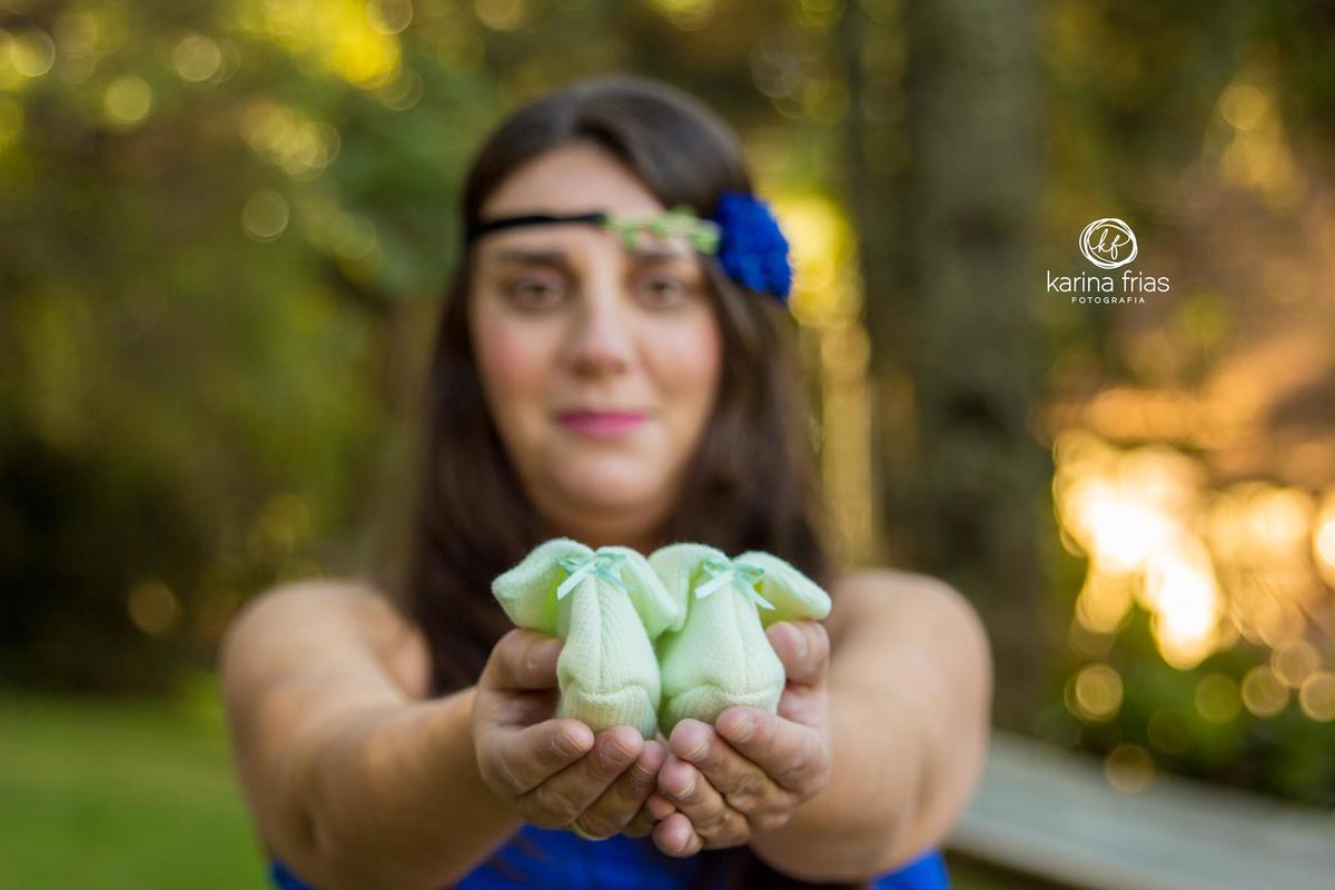 a gestante mostra os sapatinhos do bebe em suas fotos de gravida