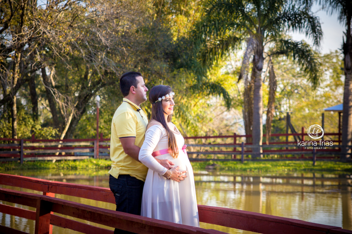 Pai e mãe contemplam a paisagem no book externo de gestante