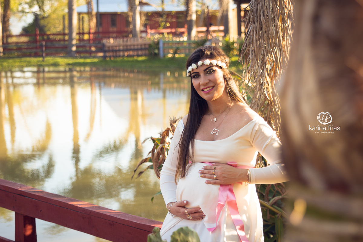 A gestante coloca as mãos na barriga para as fotos de seu ensaio