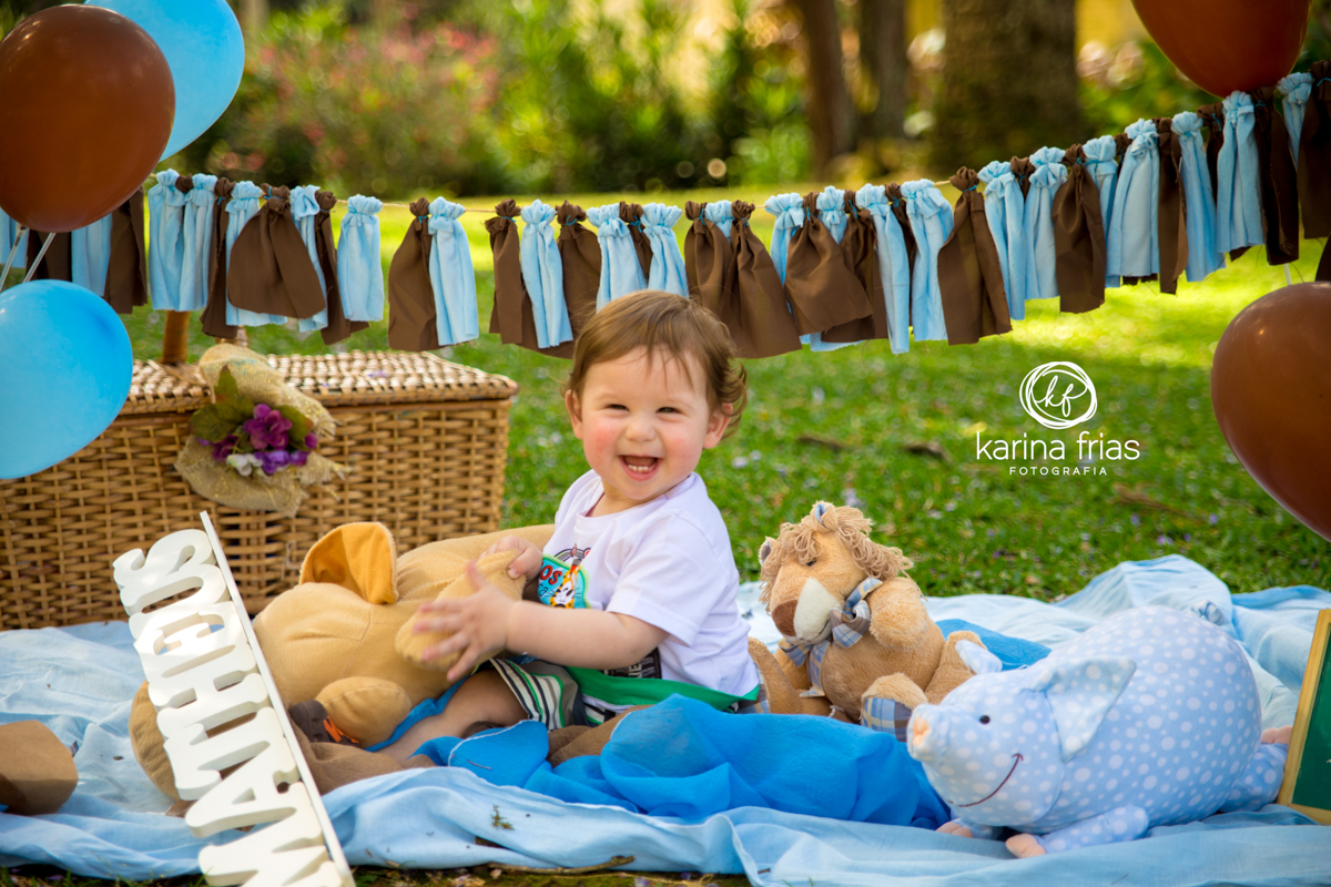A CRIANÇA ESTÁ SENTADA NO CENÁRIO MONTADO PARA AS FOTOS DO SMASH THE CAKE