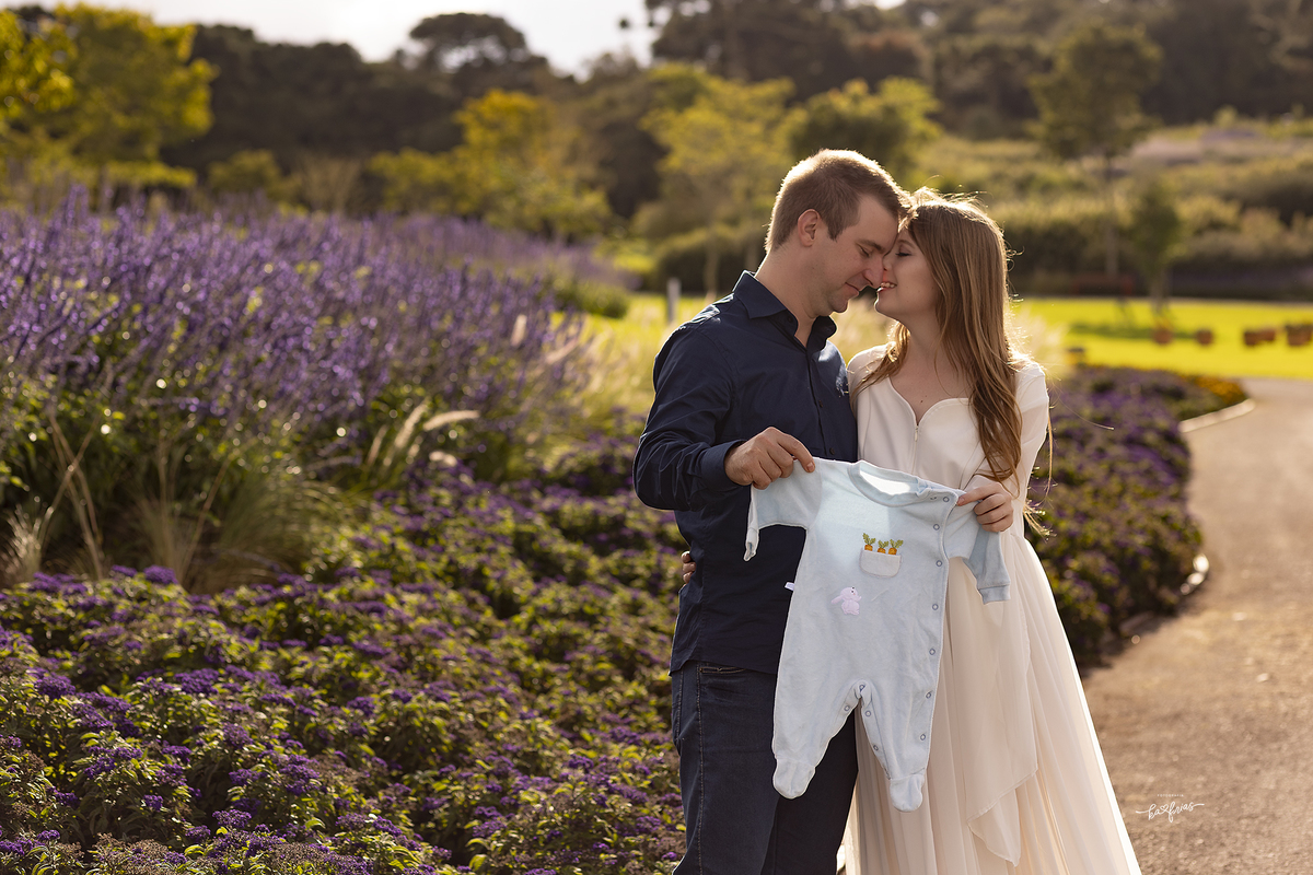 os pais mostram a roupa do bebe nas fotos de gestante