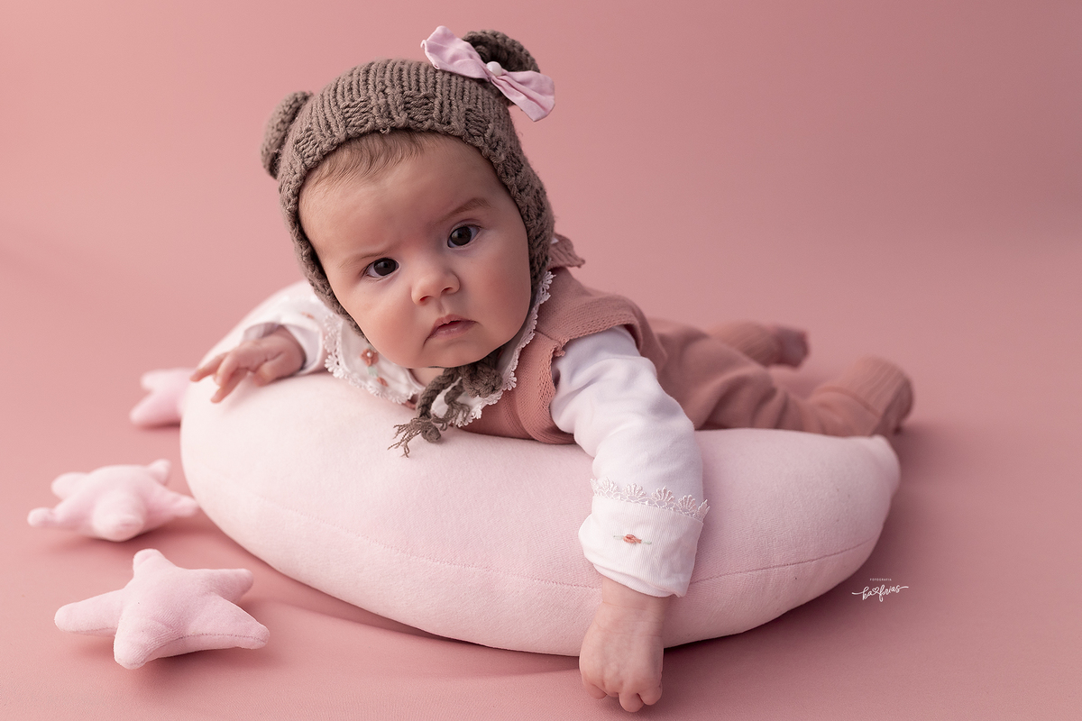 a bebe esta deitada para as fotos de acompanhamento mensal.