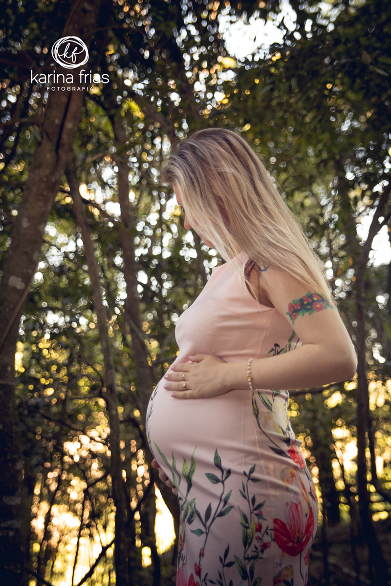 a gestante olha fixa para a barriga em seu ensaio externo