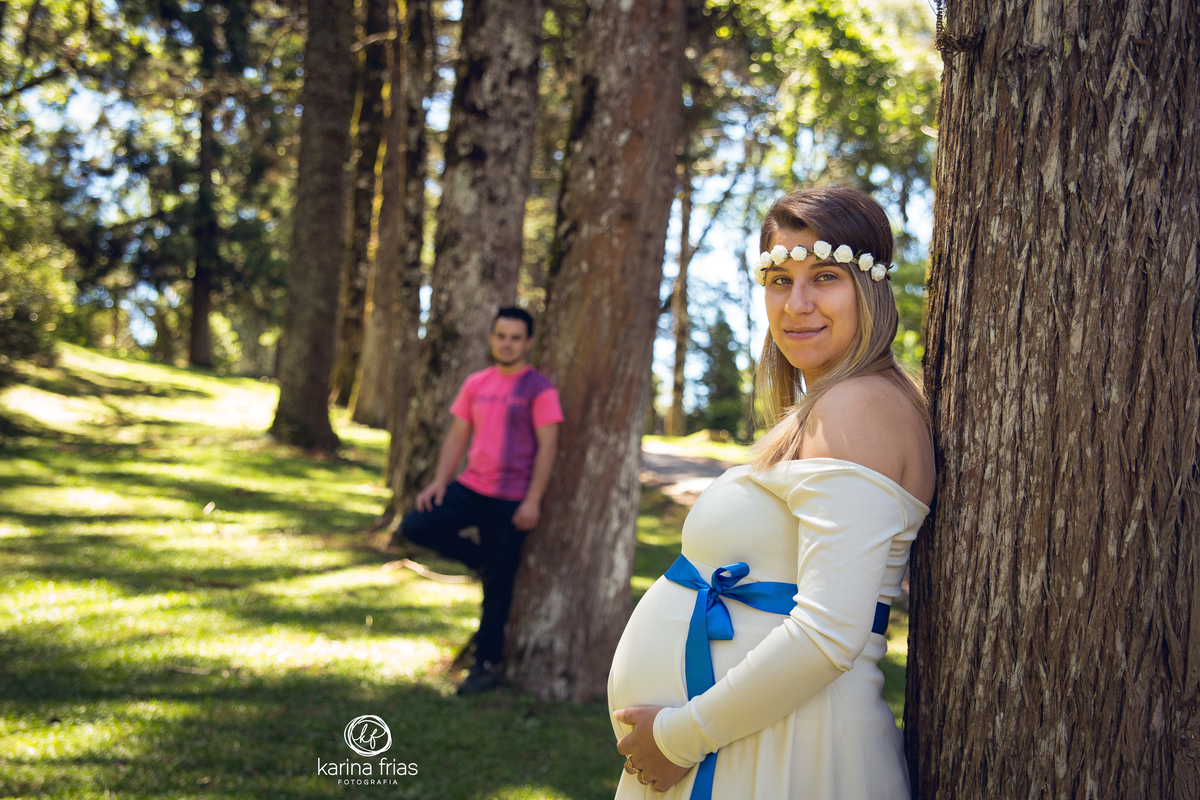 o pai ao fundo fica desfocado para a gestante ficar nitida em seu book externo