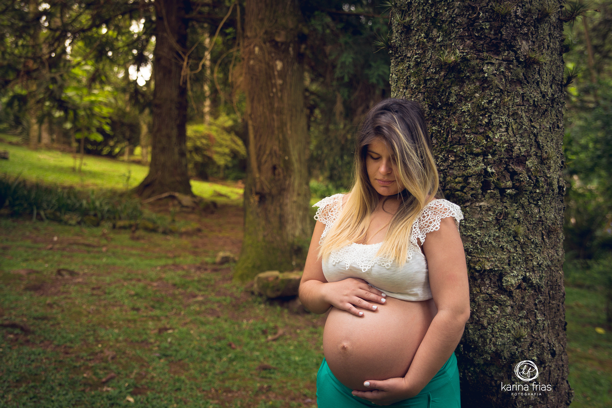 a gestante segura a barriga em meio a nbatureza para as fotos de gestante em caxias do sul-rs
