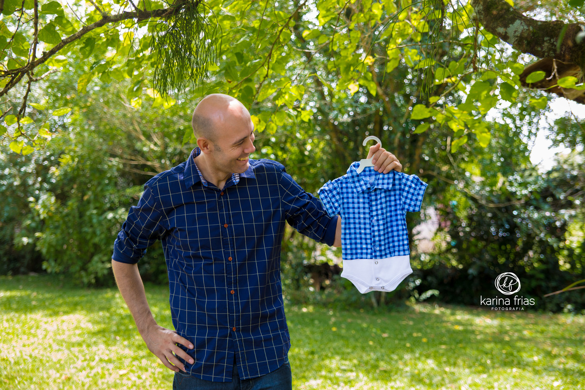no book de gestante o pai segura a roupa do bebe