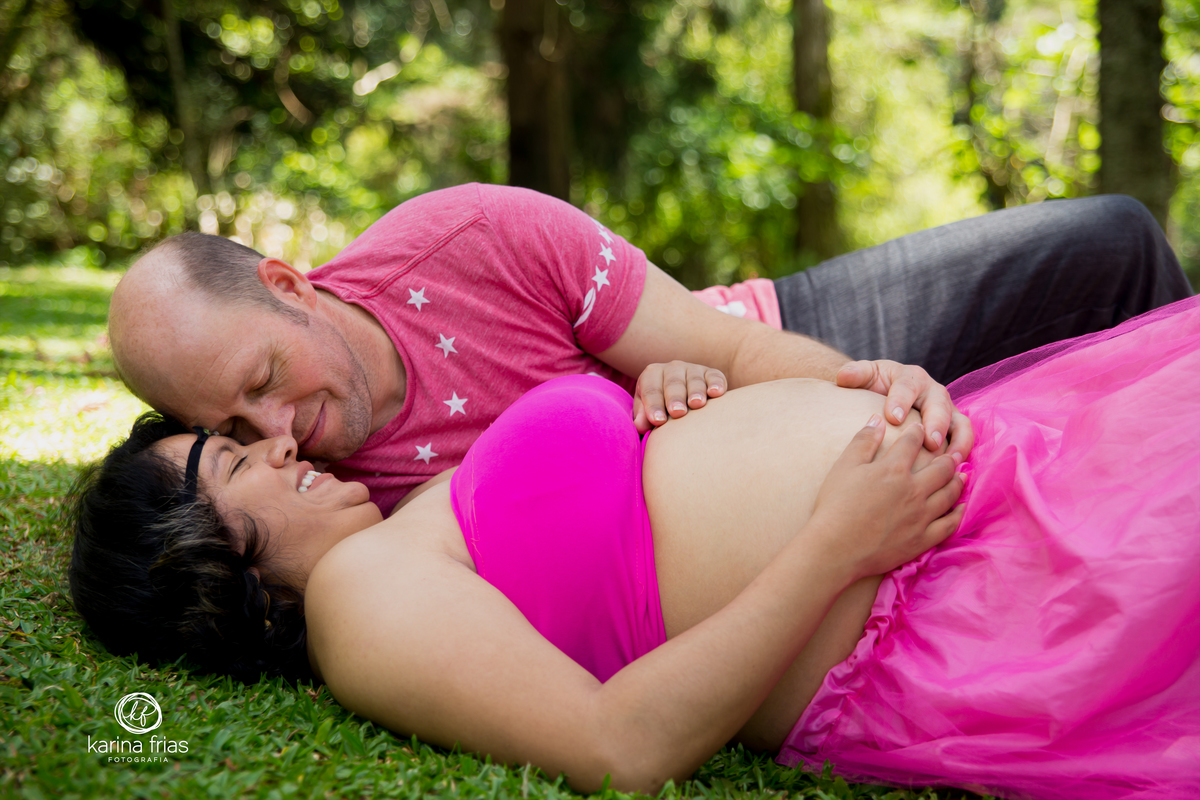 o pai faz carinho na gestante enquanto a fotografa registra o momento