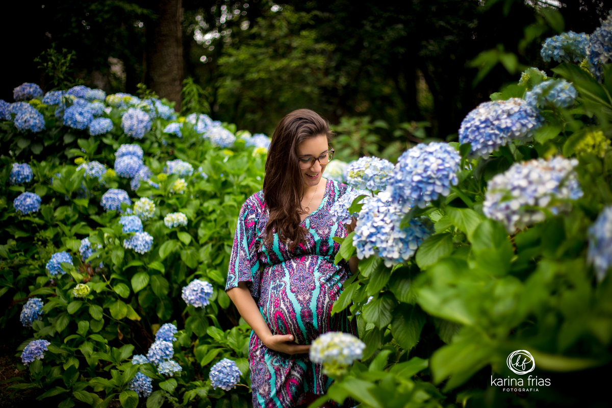 A GESTANTE OLHA AS FLORES ENQUANTO A FOTOGRAFA DE FAMILIA, KARINA FRIAS DE CAXIAS DO SUL-RS, REGISTRA O MOMENTO