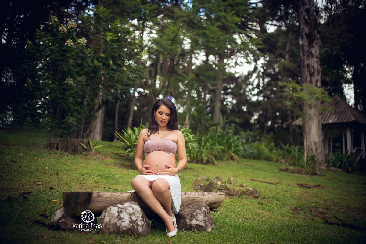 a gestante olha a barriga enquanto a fotografa de gestante, karina frias de caxias do sul-rs, registra o momento