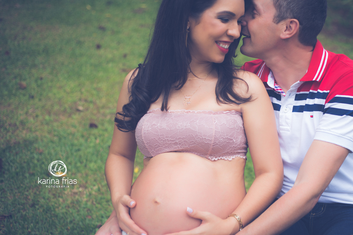 o pai cochicha algo no ouvido da gestante enquanto a fotografa de familia, karina frias, registra