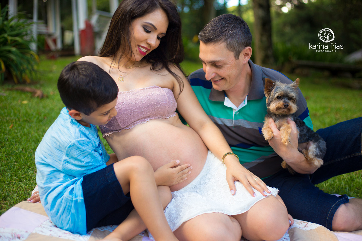 a familia olha para a barriga no ensaio externo de gestante